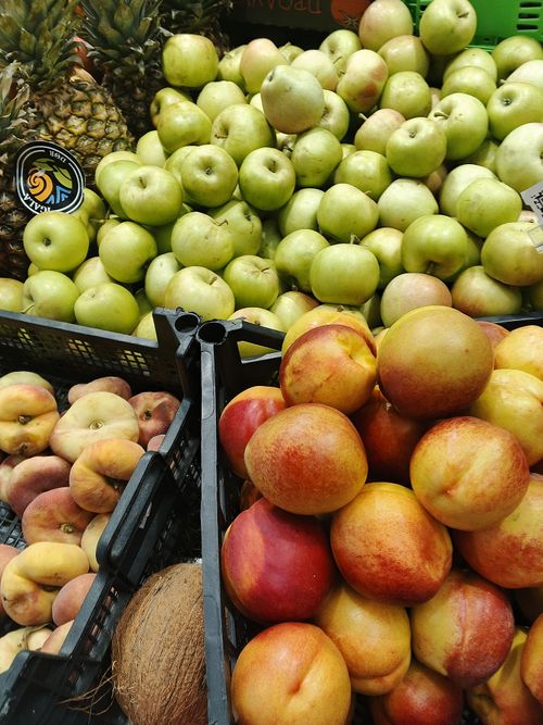 Free Colorful assortment of fresh apples, peaches, and pineapples at a market. Perfect for healthy lifestyle visuals. Stock Photo