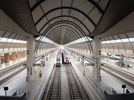 A modern railway station in Sevilla featuring trains and geometric architecture.