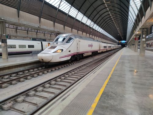 Free Renfe train positioned at the Seville Santa Justa station, showcasing modern railway architecture. Stock Photo