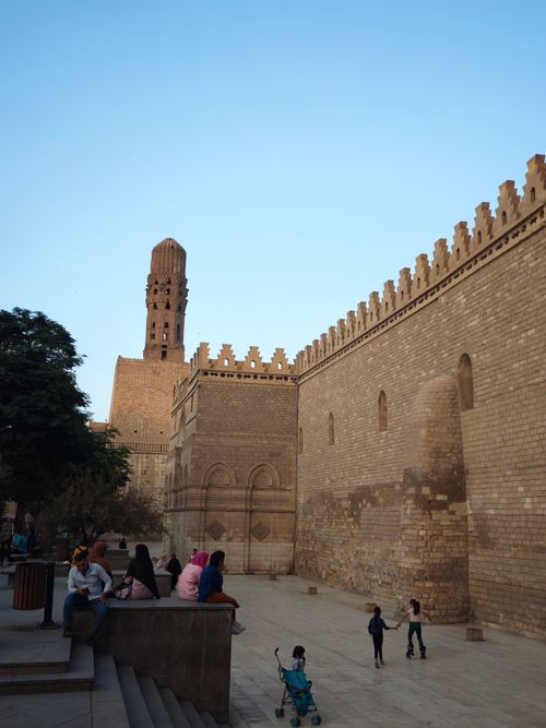Free People enjoy the vibrant atmosphere near Cairo's iconic stone wall and minaret. Stock Photo