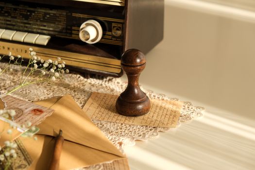 A nostalgic still life featuring a vintage radio, handwritten letters, and a wooden stamp.