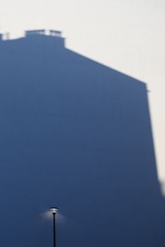 Street lamp casting shadow on building in Warsaw, Poland. Minimalist architecture photo.