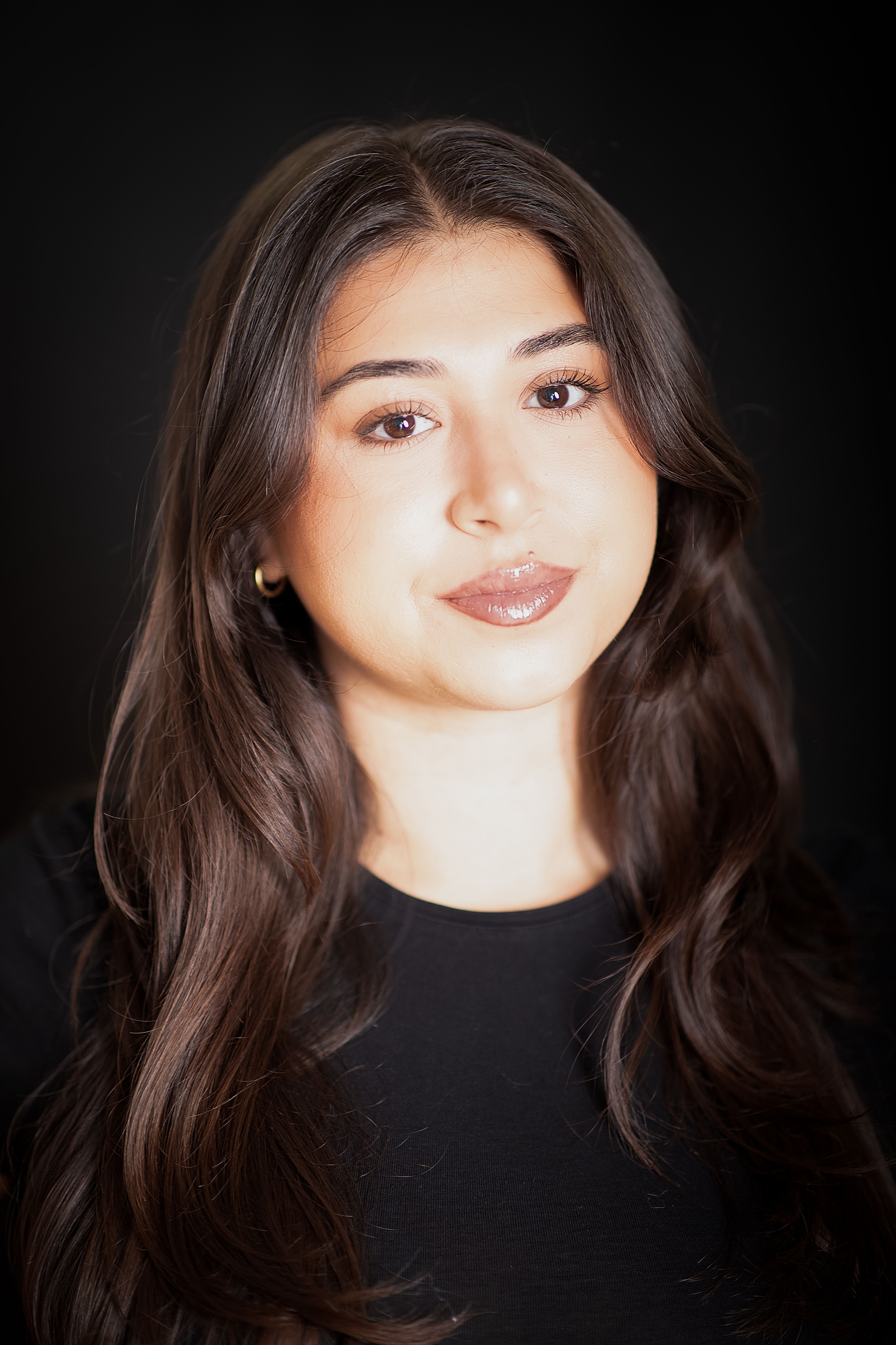 Studio portrait of a young woman with long brown hair and a serene expression.