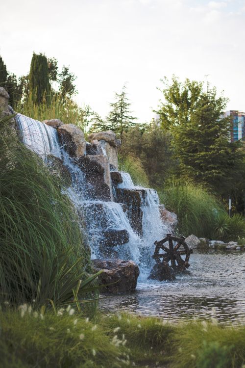 Free Serene waterfall with water wheel in a lush İstanbul park setting. Stock Photo