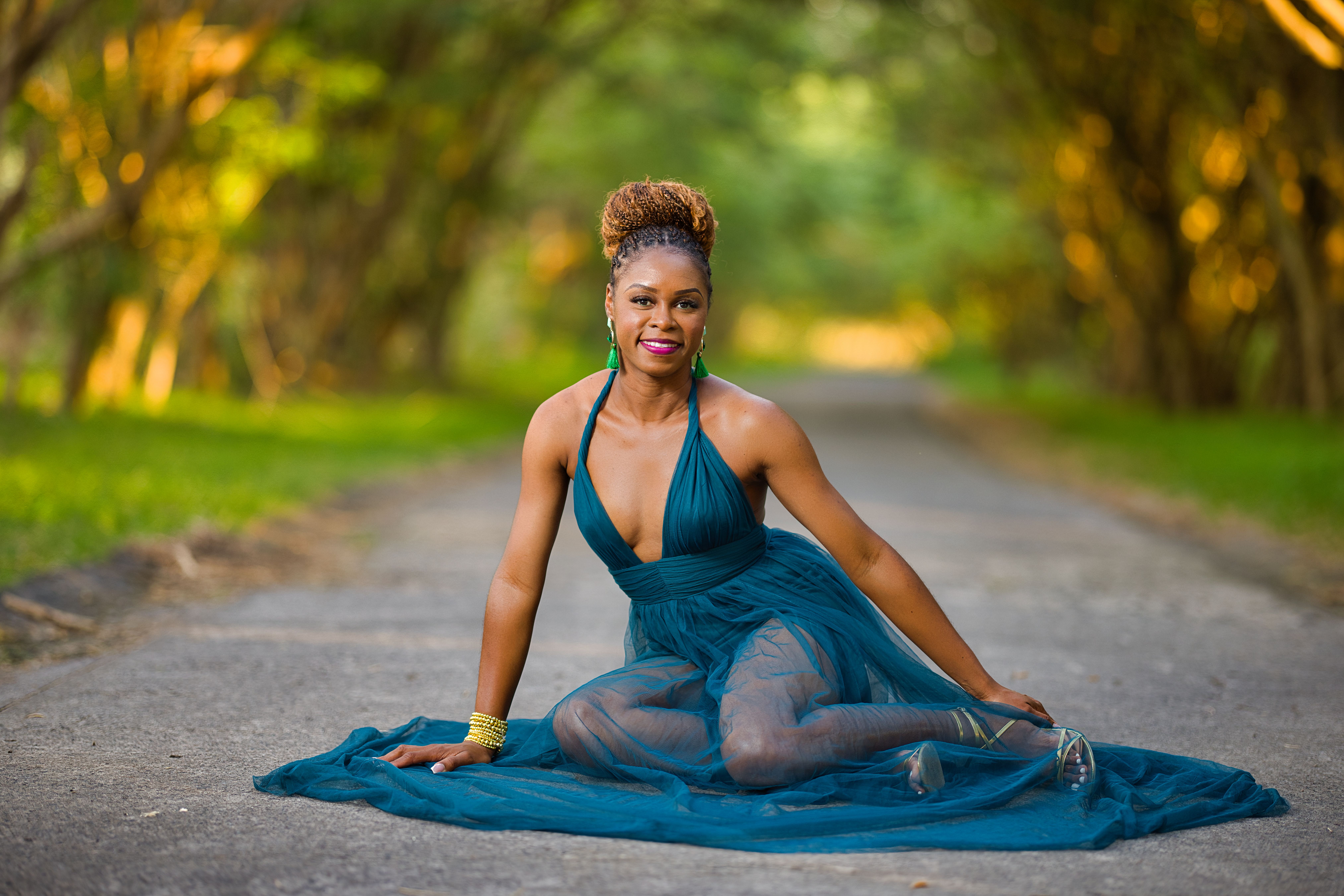 A woman in a blue dress sits gracefully on a tree-lined path at Frigate Bay.