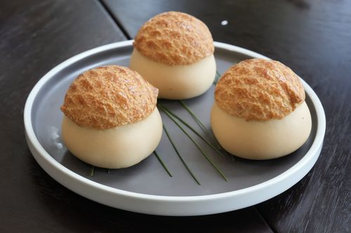 Free Three elegant cream puffs arranged on a modern gray plate with chive garnish. Stock Photo