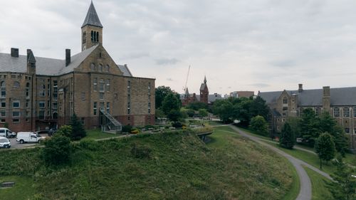 Free Aerial view of a historic university campus featuring a prominent clock tower and traditional architecture. Stock Photo