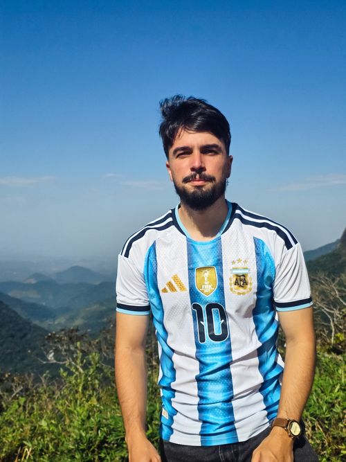Free Man in Argentina football jersey posing outdoors with scenic mountainous backdrop. Stock Photo