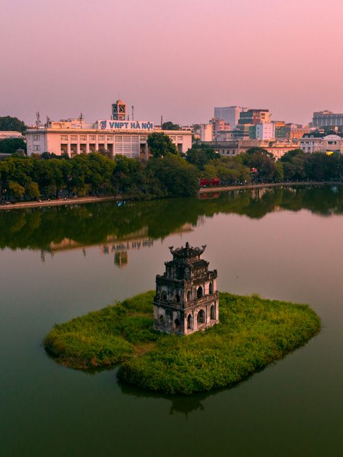 Free Captivating aerial view of Turtle Tower on Hoan Kiem Lake in Hanoi during sunset, showcasing Vietnam's vibrant cityscape. Stock Photo