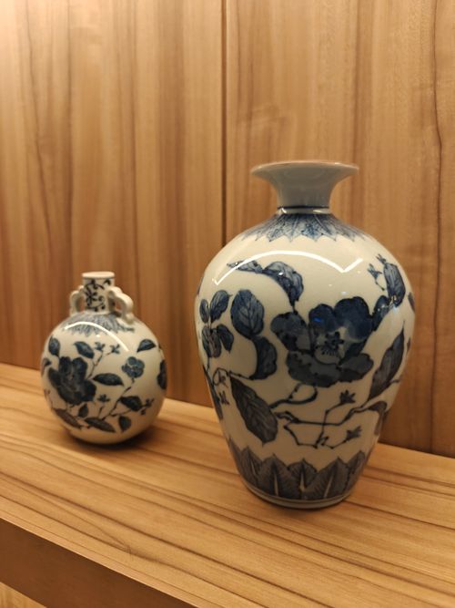 Free Two Japanese porcelain vases with floral designs on a wooden shelf, showcasing traditional craft. Stock Photo