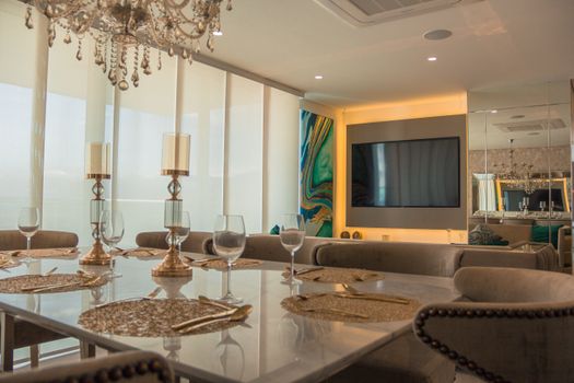 An elegant and modern dining room with plush seating and a crystal chandelier. Ideal for luxury home settings.