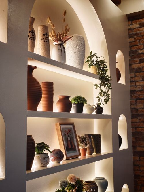 Free A stylish shelf displaying decorative vases, plants, and framed art in a cozy setting. Stock Photo