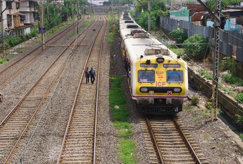 Free A yellow passenger train travels on urban railway tracks during the day. Stock Photo