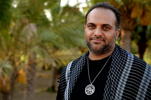 Free A serene portrait of a man wearing traditional attire in a palm grove in Karbala, Iraq. Stock Photo