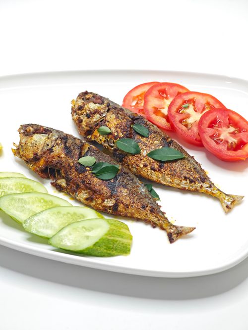 Free Grilled seasoned fish served with fresh sliced tomatoes and cucumbers on a white plate. Stock Photo