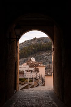 Discover the rustic beauty through an archway in Cuenca's historic district.