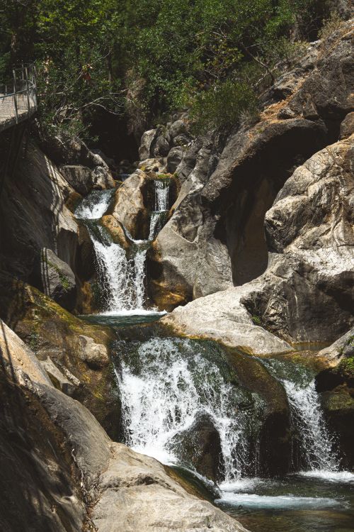 Free Discover the natural beauty of a cascading waterfall flowing through rocky terrain in Türkiye's wilderness. Stock Photo