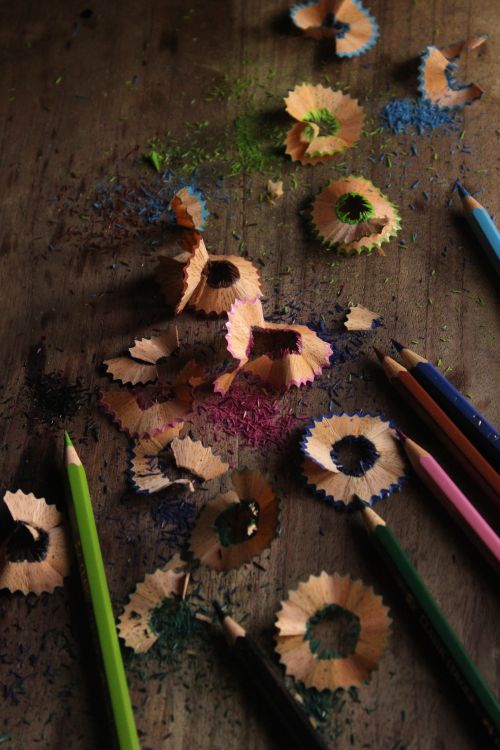 Free Vibrant colored pencil shavings scattered on a rustic wooden surface. Stock Photo