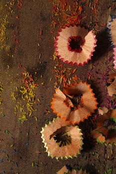 Vibrant pencil shavings scattered on a rustic wooden surface, highlighting creativity.
