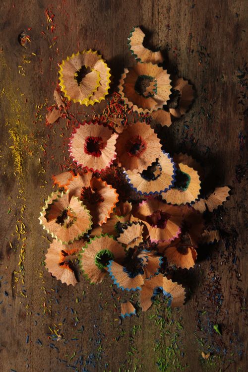 Free Colorful pencil shavings scattered on wooden surface, creating an artistic pattern. Stock Photo