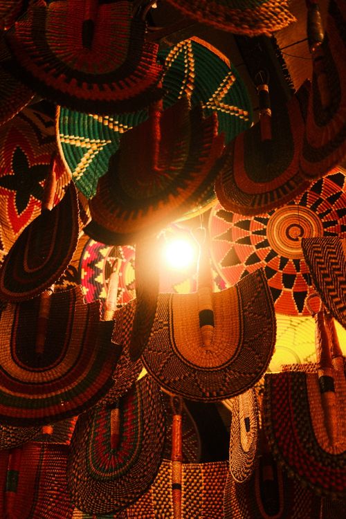 Free Colorful woven fans hanging against warm light in Chefchaouen, Morocco. Artistic and cultural display. Stock Photo