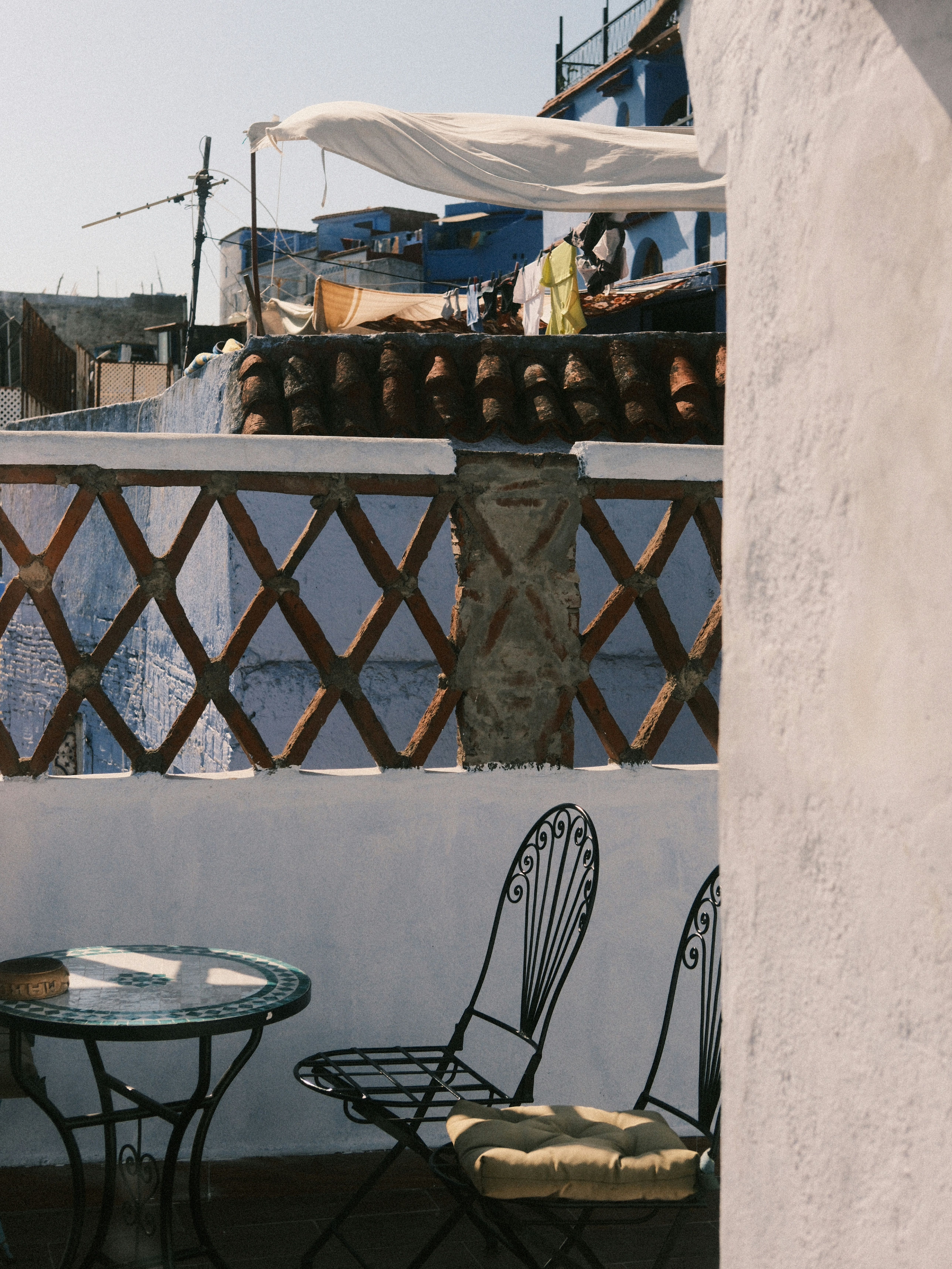 Sunlit rooftop scene with chairs in Chefchaouen, Morocco showcasing traditional architecture.