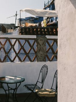 Sunlit rooftop scene with chairs in Chefchaouen, Morocco showcasing traditional architecture.
