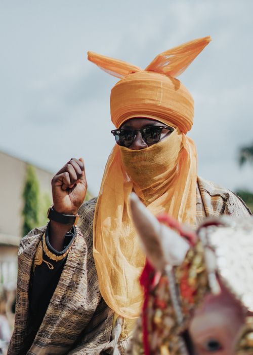 Free A man in traditional African attire rides a decorated horse at a vibrant cultural festival. Stock Photo