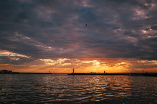 Free Dramatic sunset over the ocean with vibrant clouds and a serene horizon. Stock Photo