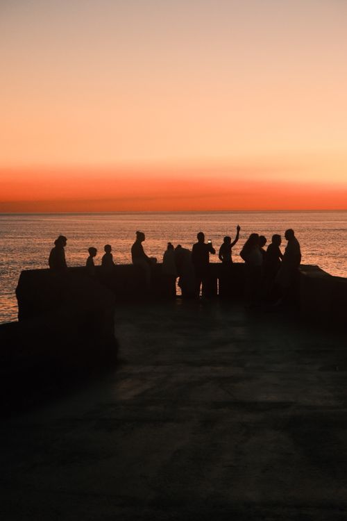 Free People silhouetted against a vibrant sunset over the horizon, creating a serene and picturesque scene. Stock Photo