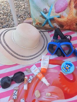 Flat lay of essential summer beach items including a straw hat, sunglasses, snorkel mask, and sunscreen.