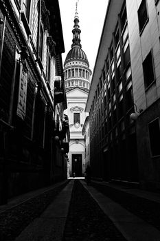 Black and white photo of a narrow street leading to a stunning dome, capturing architectural beauty.