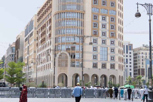 A vibrant street scene in Madinah, Saudi Arabia, with people and modern architecture.