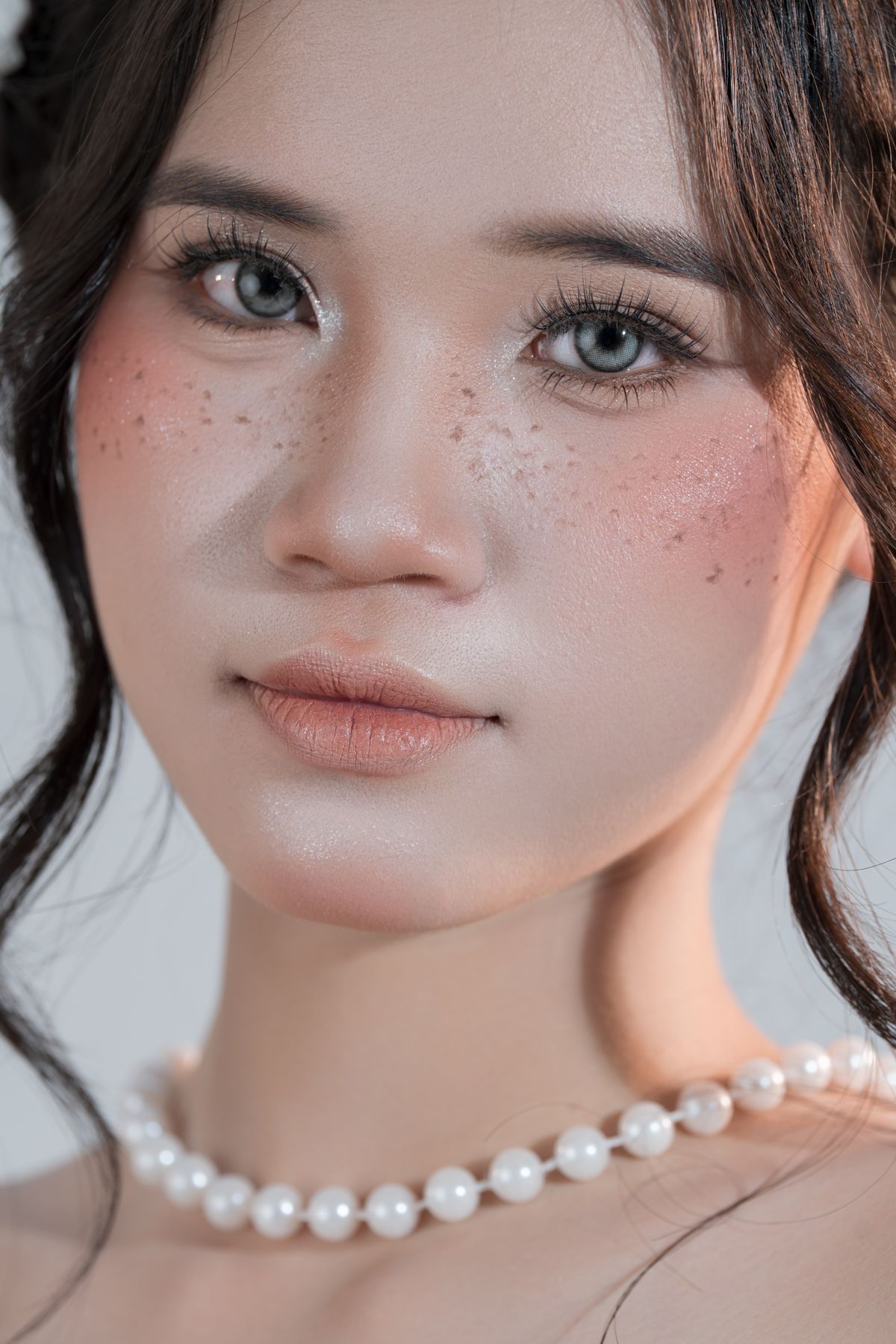 Close-up portrait of a woman with natural freckles and a soft, sun-flushed gel-cream blush look across her cheeks
