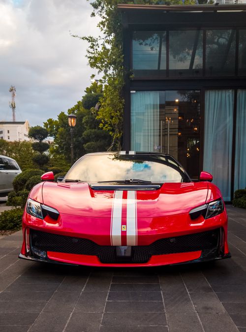 Free Front view of a sleek red sports car parked outdoors in urban environment. Stock Photo