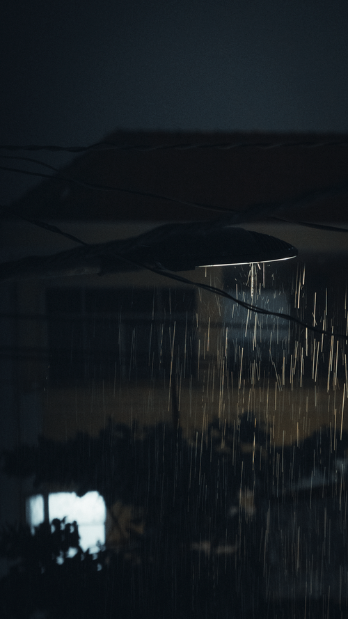 Free Moody nighttime street scene with rain under a streetlight in Ho Chi Minh City. Stock Photo