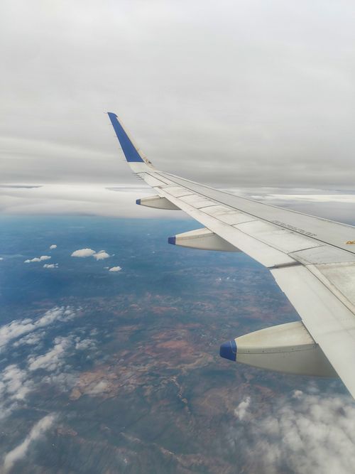 Free Scenic aerial view of landscape with airplane wing under a cloudy sky. Stock Photo
