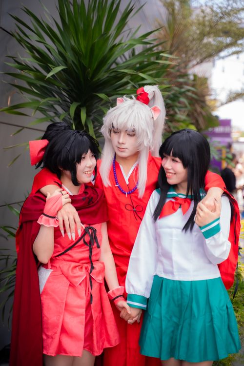 Free Three anime cosplayers in vibrant costumes embracing outdoors. Stock Photo