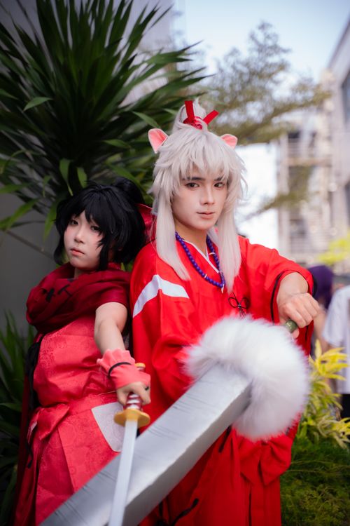 Free Two cosplayers in detailed costumes pose with a large sword outdoors. Stock Photo