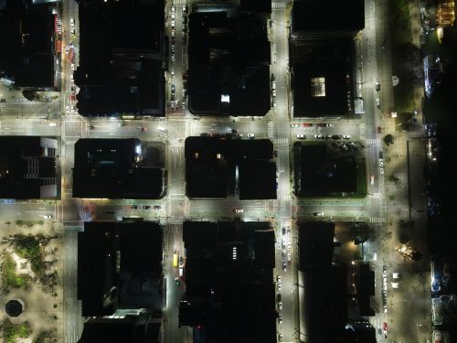 Free High-angle aerial shot of illuminated city streets and intersections at night. Stock Photo