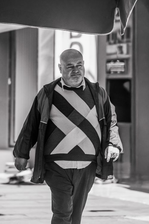 Free Monochrome portrait of a man walking on an urban street, wearing a patterned sweater. Stock Photo