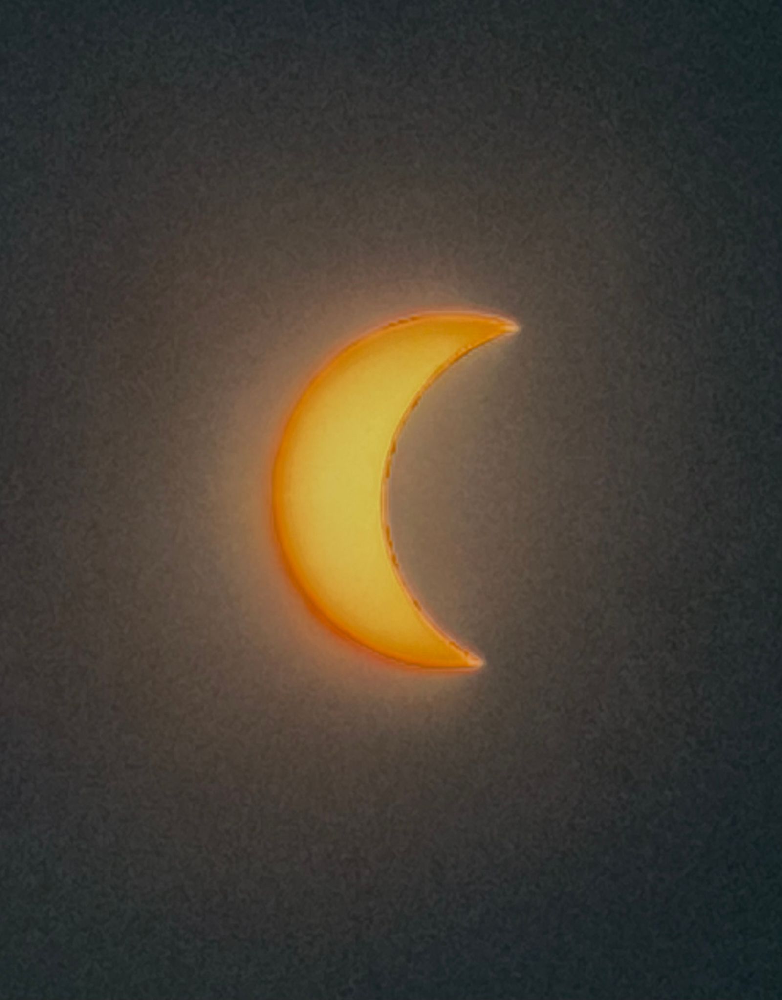 Fin croissant de l'éclipse solaire sur un ciel qui s'assombrit