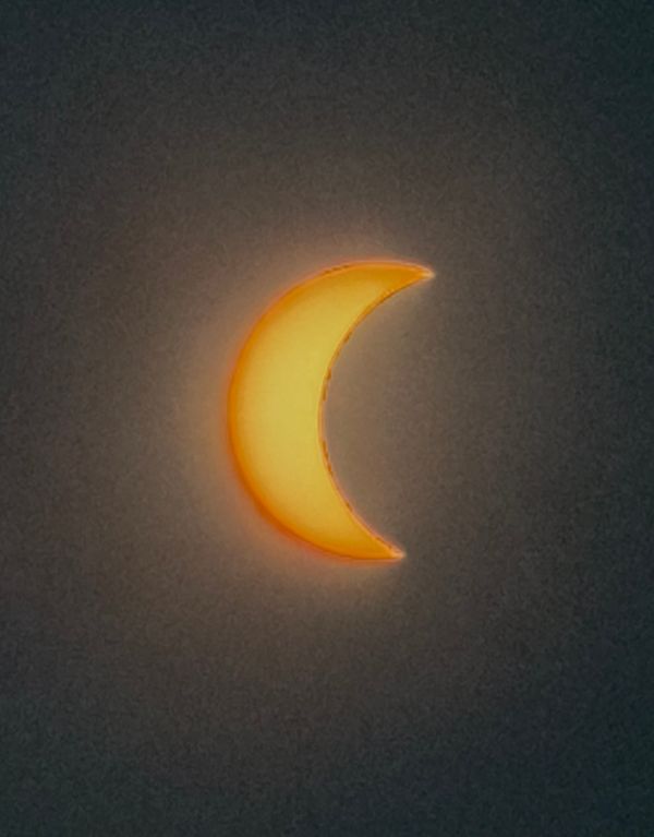 Fin croissant de l'éclipse solaire sur un ciel qui s'assombrit
