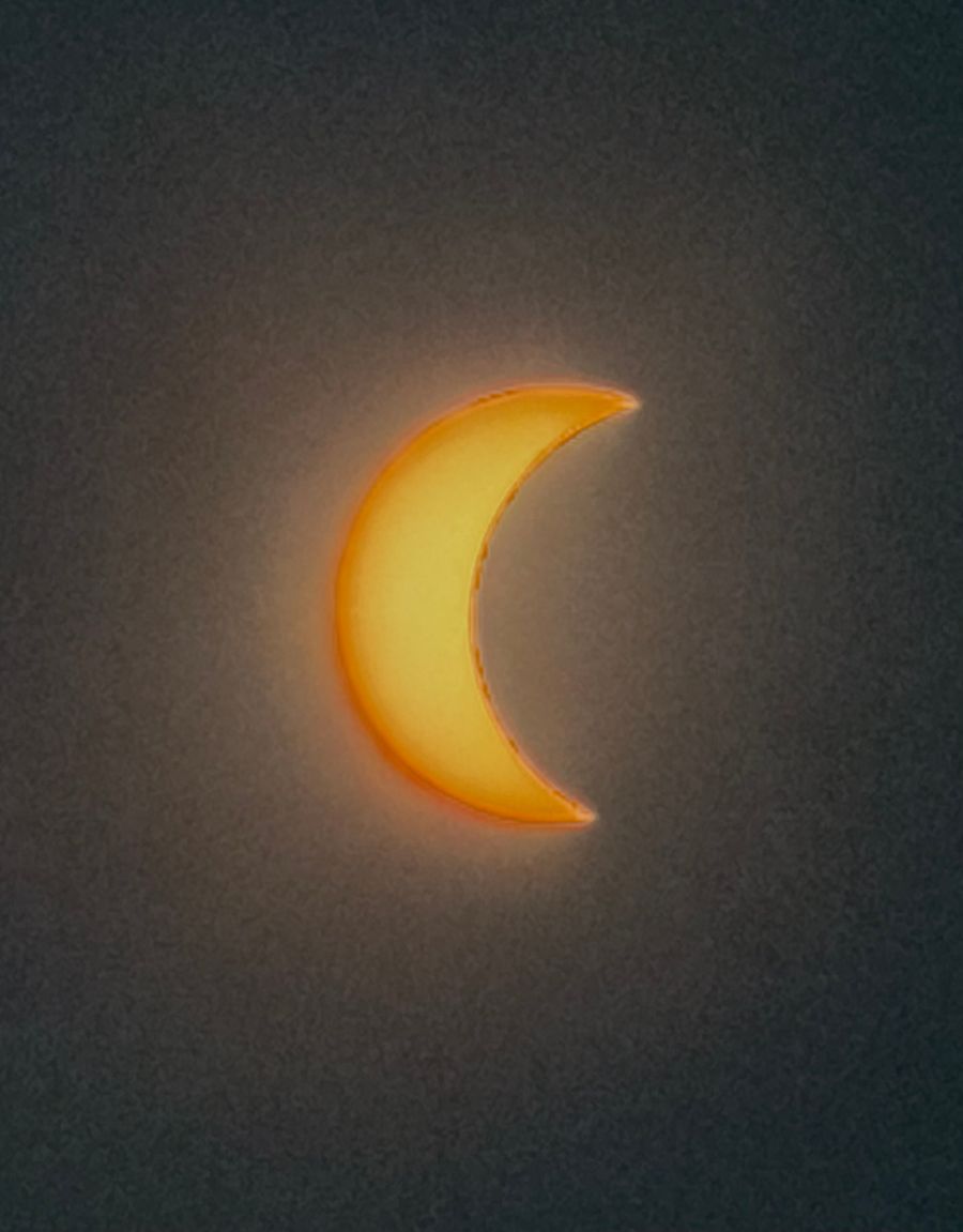 Fin croissant de l'éclipse solaire sur un ciel qui s'assombrit