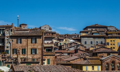 Free Captivating skyline of Siena's historic rooftops showcasing Tuscan architecture under a bright blue sky. Stock Photo