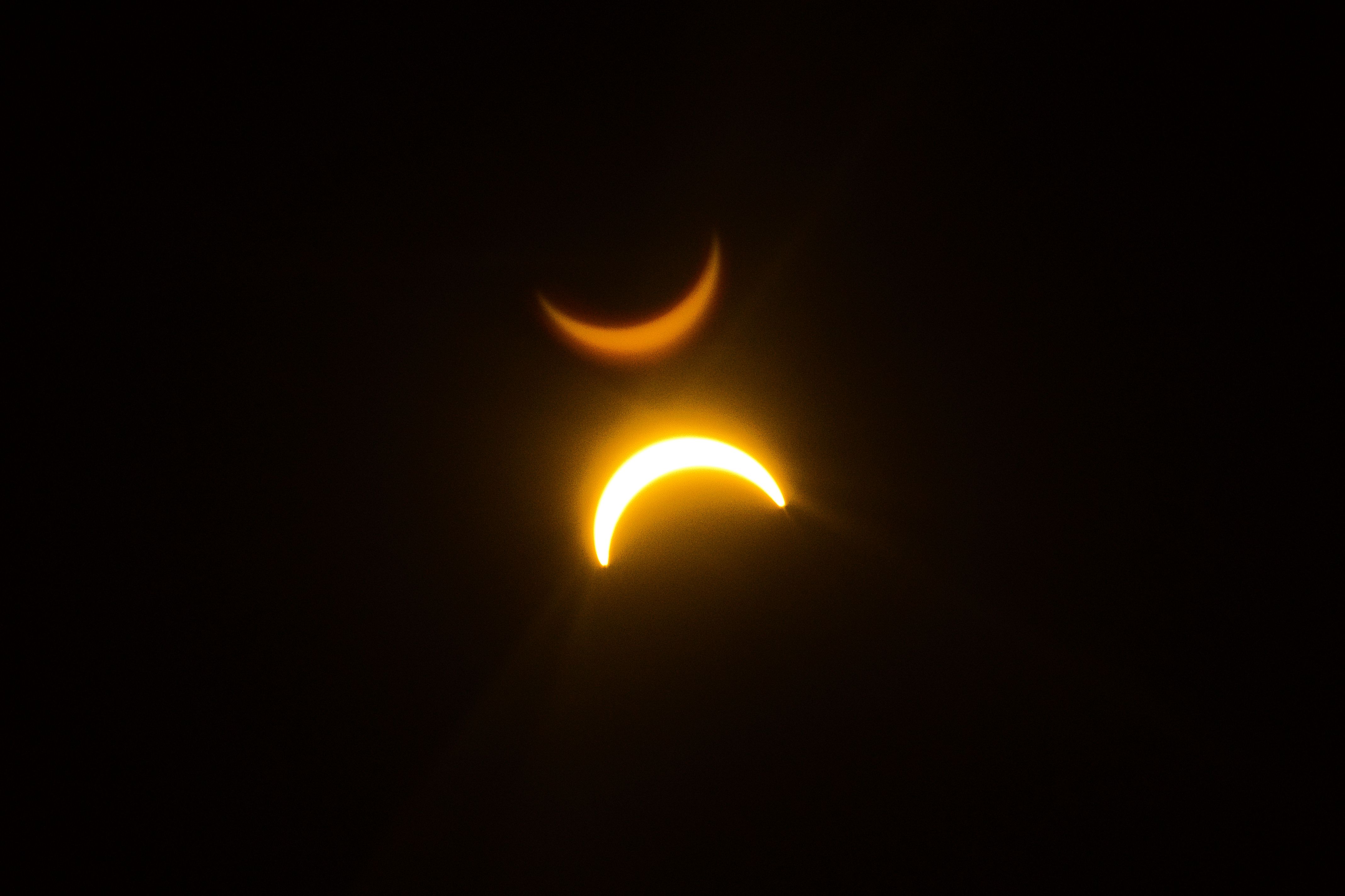 Fotomural Un fascinante eclipse solar con efecto de doble exposición que crea un espectáculo visual celestial.
