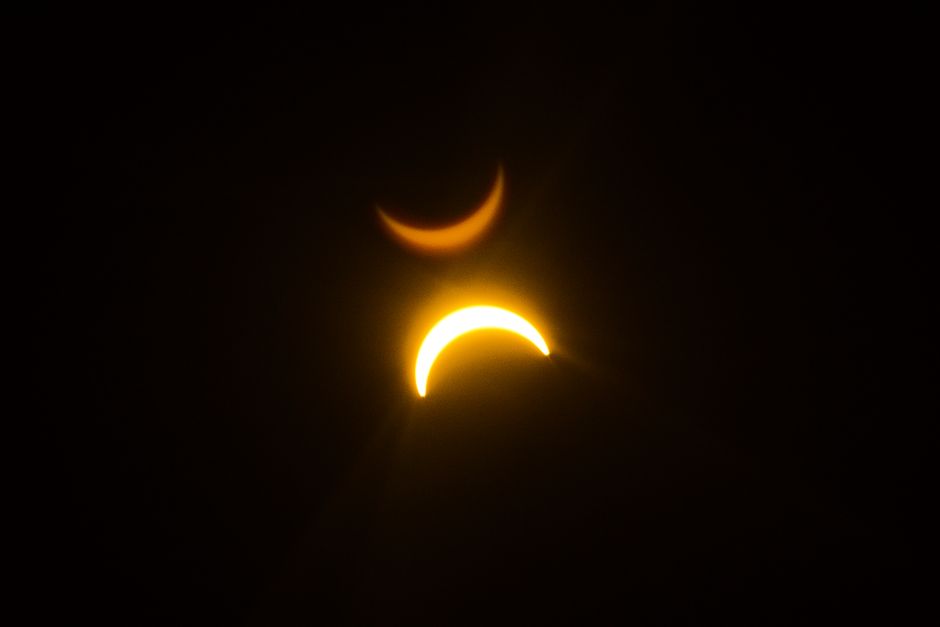 Fotomural Un fascinante eclipse solar con efecto de doble exposición que crea un espectáculo visual celestial.