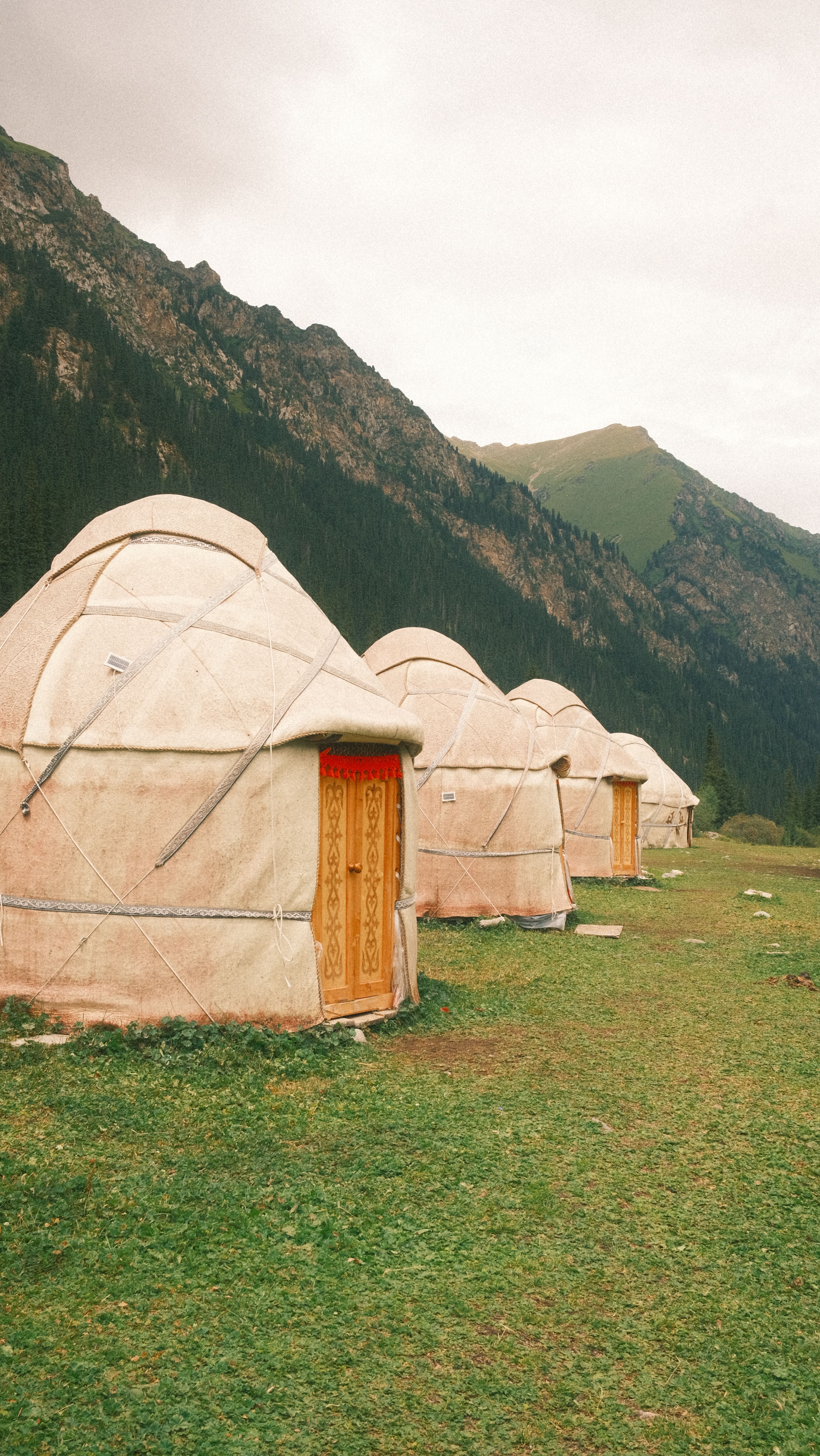 Scenic view of traditional yurts against a mountainous backdrop in Kyrgyzstan.