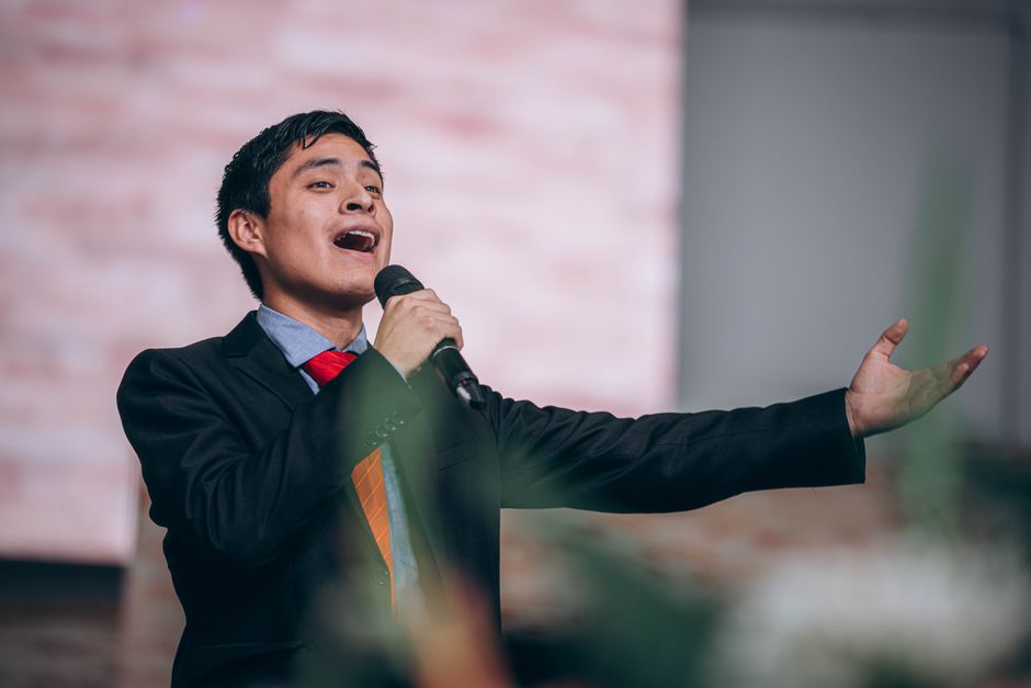 Young man in suit and tie singing passionately indoors, holding a microphone. Young man in suit and tie singing passionately indoors, holding a microphone.