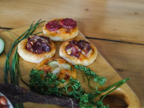 Delicious mini pizzas topped with beef biltong and herbs on a wooden board in Bujumbura, Burundi.